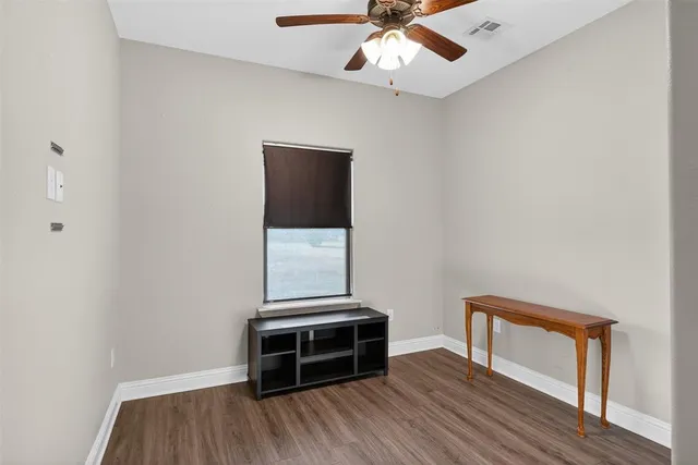 an empty room with wooden floor fan and windows