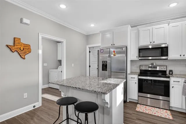 a kitchen with stainless steel appliances granite countertop a refrigerator a stove a sink and a microwave