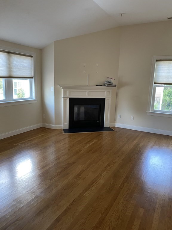 6 Essex Road, Unit 16 Ipswich, MA 01938 - Photo 5 of 14 an empty room with wooden floor fireplace and windows