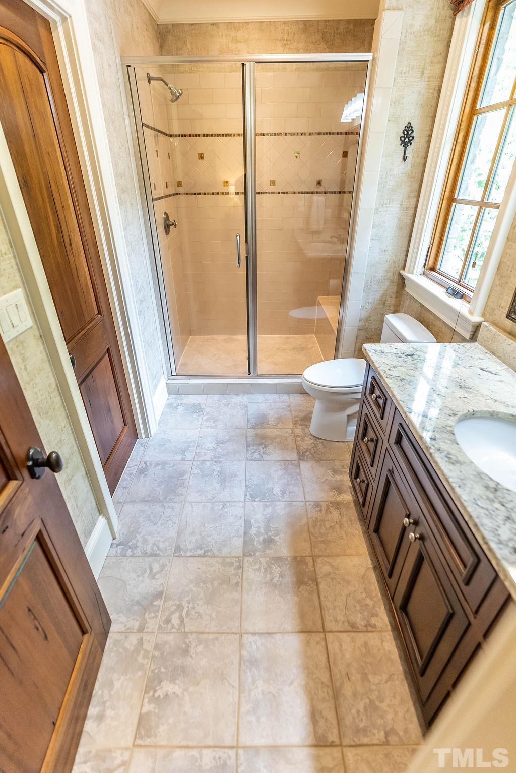 11213 Jonas Ridge Lane Raleigh, NC 27613 - Photo 49 of 100 a bathroom with a granite countertop sink a toilet and a shower