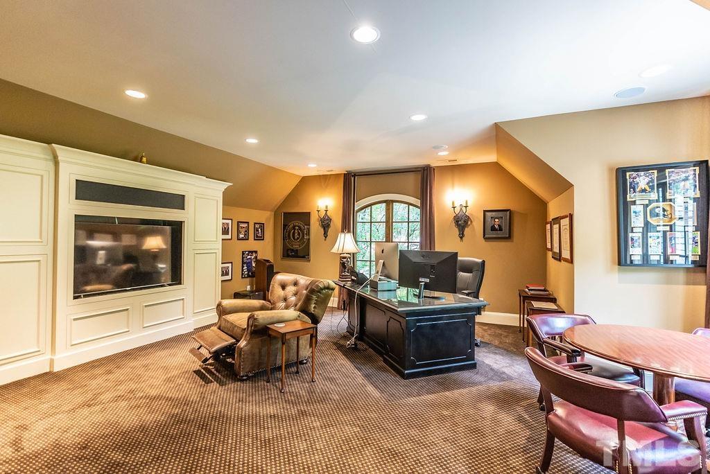 11213 Jonas Ridge Lane Raleigh, NC 27613 - Photo 64 of 100 a living room with furniture a flat screen tv and a floor to ceiling window