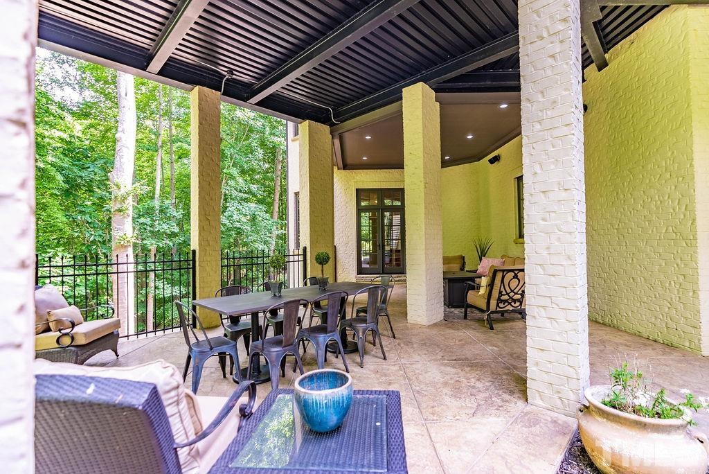 11213 Jonas Ridge Lane Raleigh, NC 27613 - Photo 86 of 100 a view of a patio with table and chairs potted plants and wooden floor