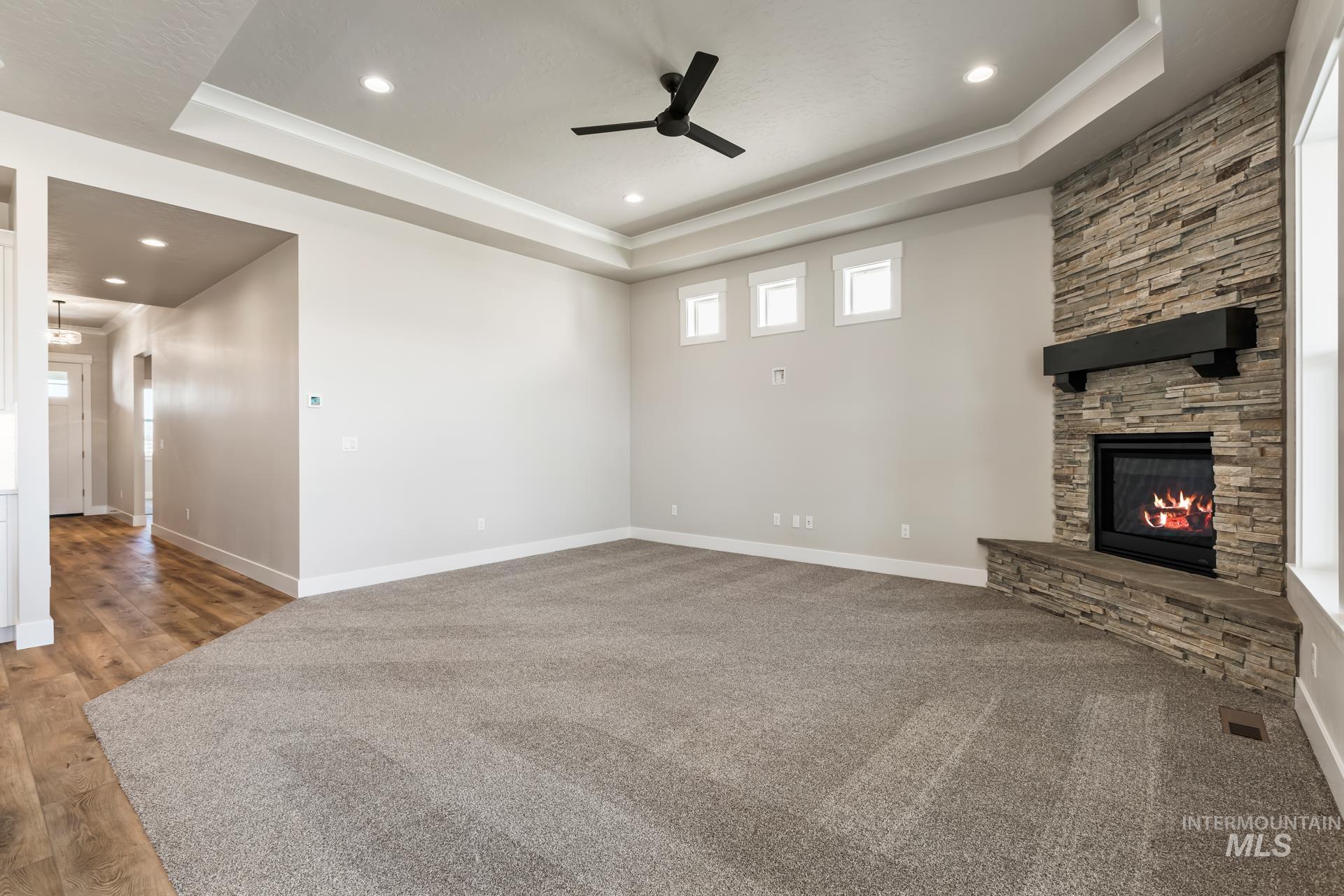 385 South Strut Way Boise, ID 83716 - Photo 14 of 30 Unfurnished living room featuring a ceiling fan, a tray ceiling, a fireplace, and recessed lighting