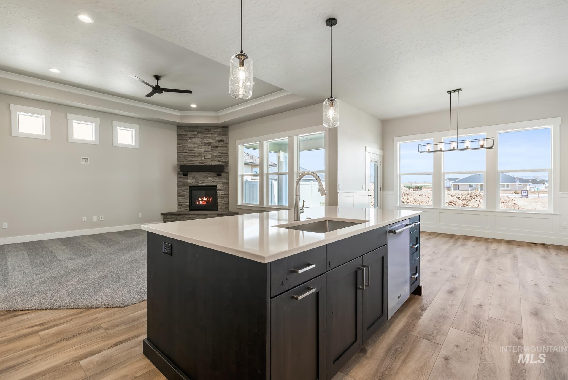 385 South Strut Way Boise, ID 83716 - Photo 30 of 30 Kitchen with dark cabinets, hanging light fixtures, a fireplace, a tray ceiling, and open floor plan