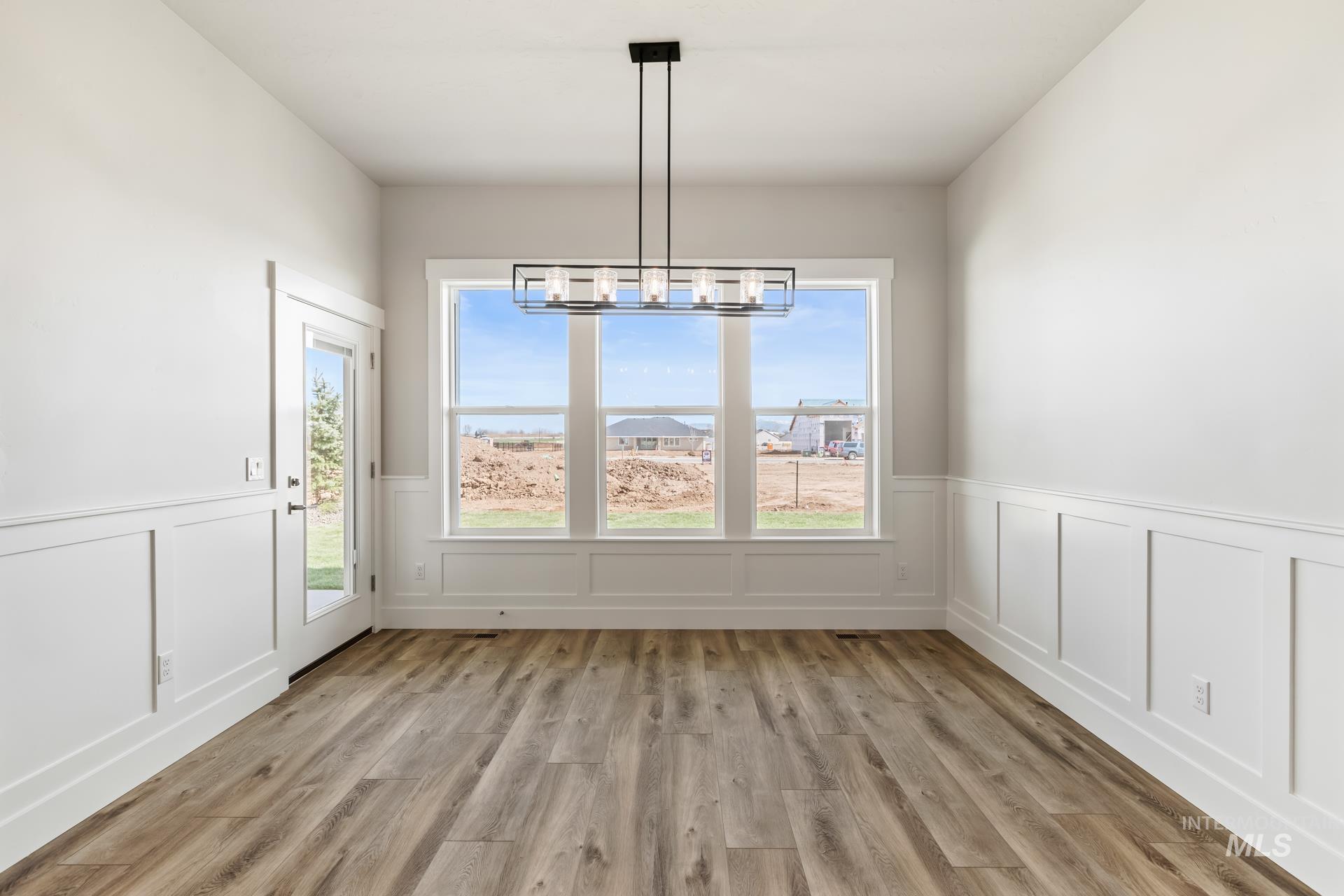 385 South Strut Way Boise, ID 83716 - Photo 20 of 30 Unfurnished dining area with light wood finished floors, a chandelier, and wainscoting