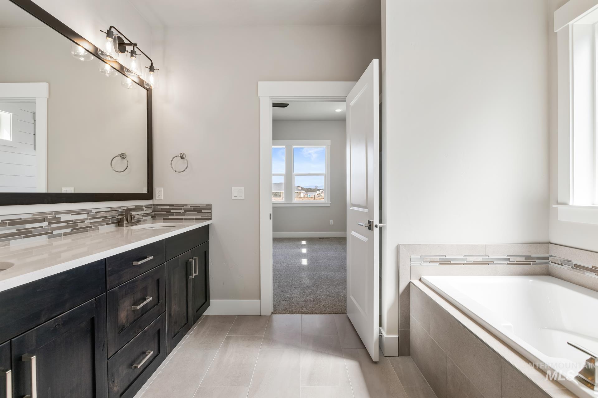 385 South Strut Way Boise, ID 83716 - Photo 24 of 30 Full bath featuring double vanity, a garden tub, light tile patterned floors, light colored carpet, and tasteful backsplash