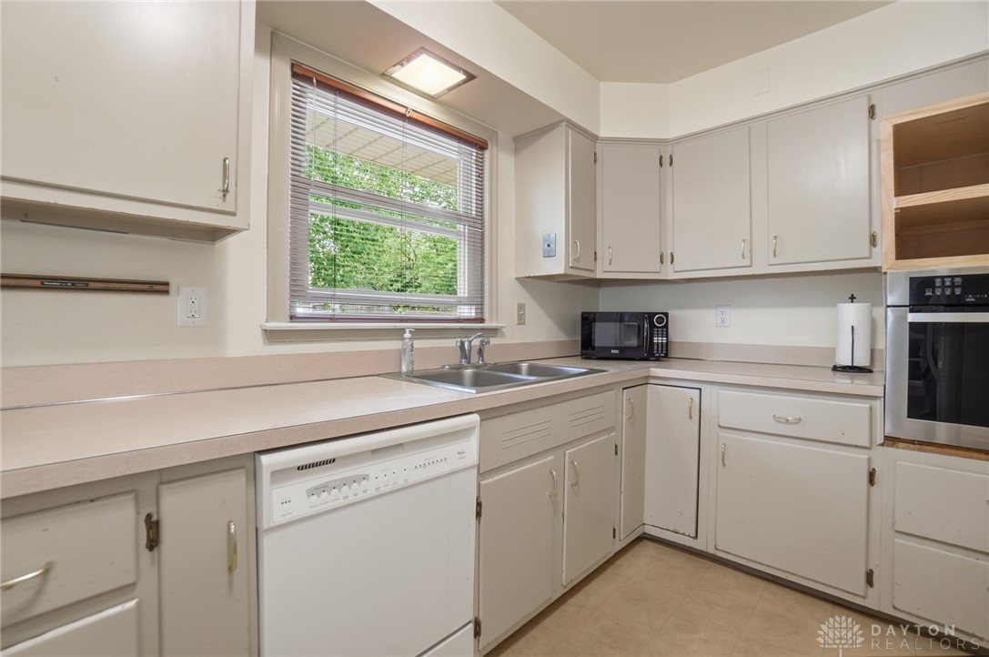 6119 Flemington Road Dayton, OH 45459 - Photo 15 of 76 This kitchen offers a practical layout with ample cabinetry and a bright window overlooking lush greenery.