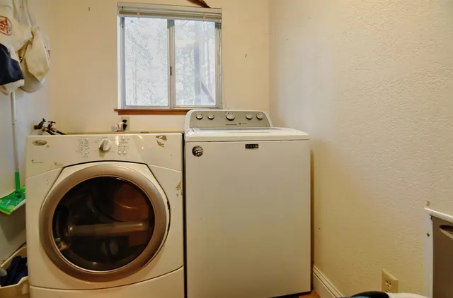 a view of a backyard with table and chairs potted plants and large tree