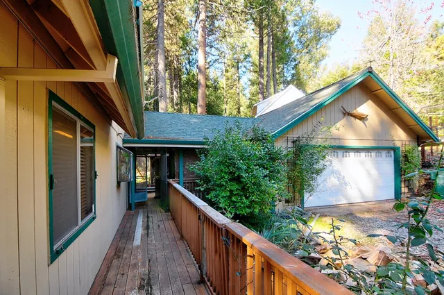 a view of a house with brick walls plants and large tree