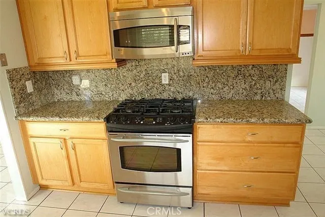 a kitchen with granite countertop white cabinets and stainless steel appliances