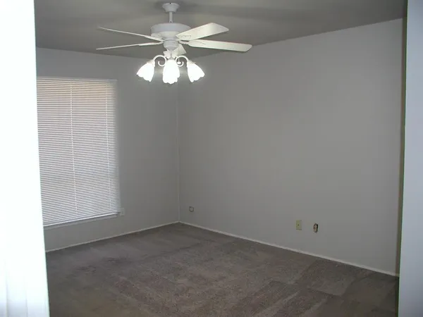an empty room with a chandelier fan and windows