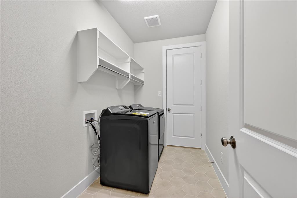 4123 Windy Point Court Oak Point, TX 75068 - Photo 22 of 29 Dedicated utility space featuring honeycomb floor tiling, built-in shelving, and a hanging rod