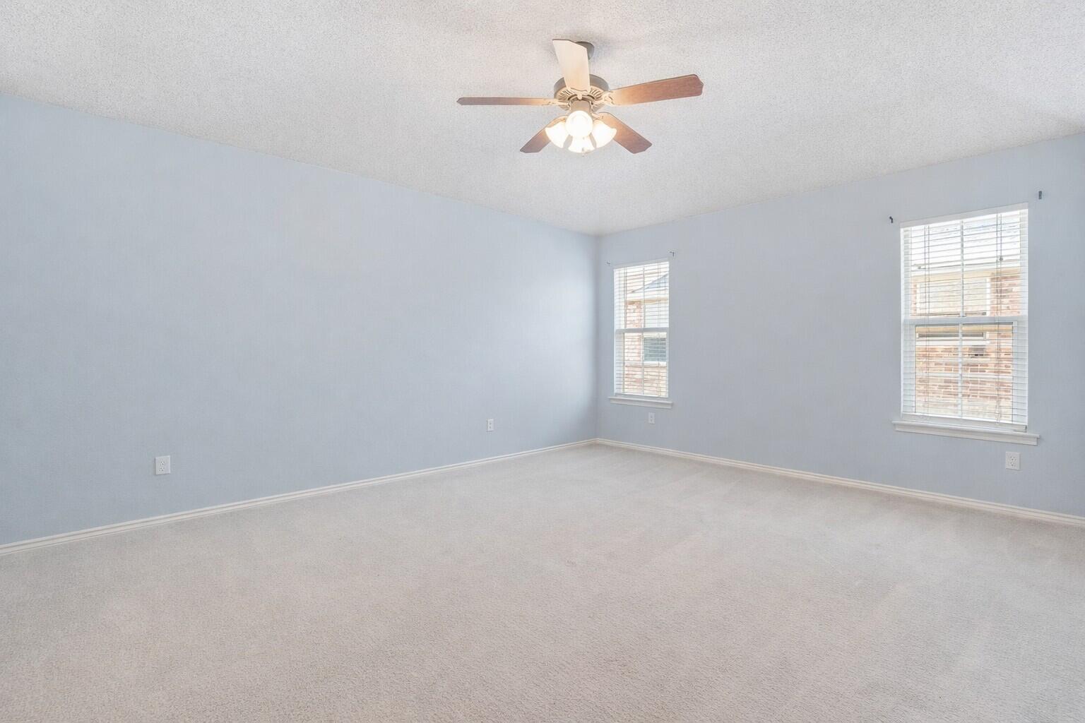 6115 100th Street Lubbock, TX 79424 - Photo 15 of 27 an empty room with windows and fan