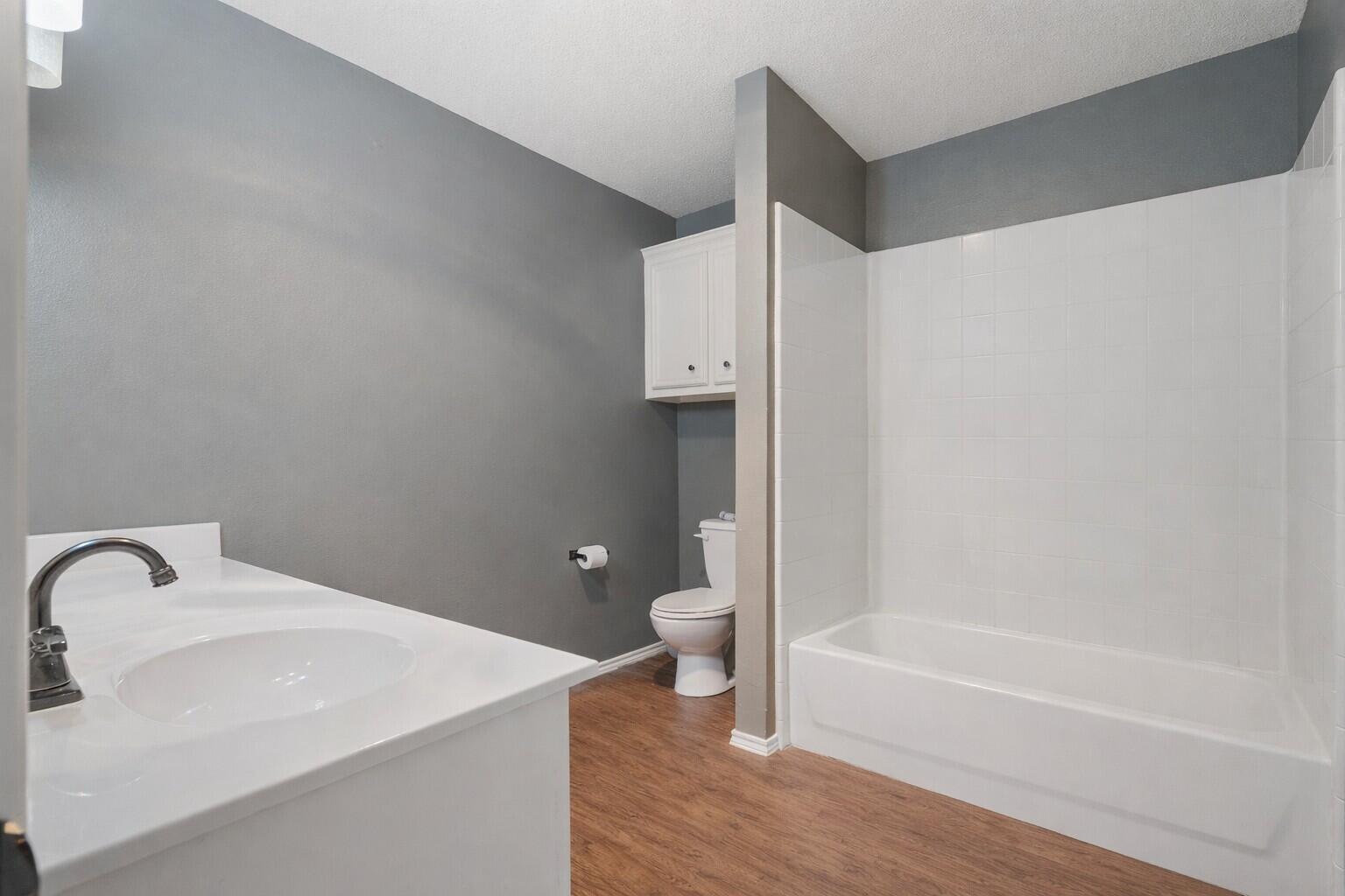 6115 100th Street Lubbock, TX 79424 - Photo 21 of 27 a bathroom with a tub shower vanity and a sink