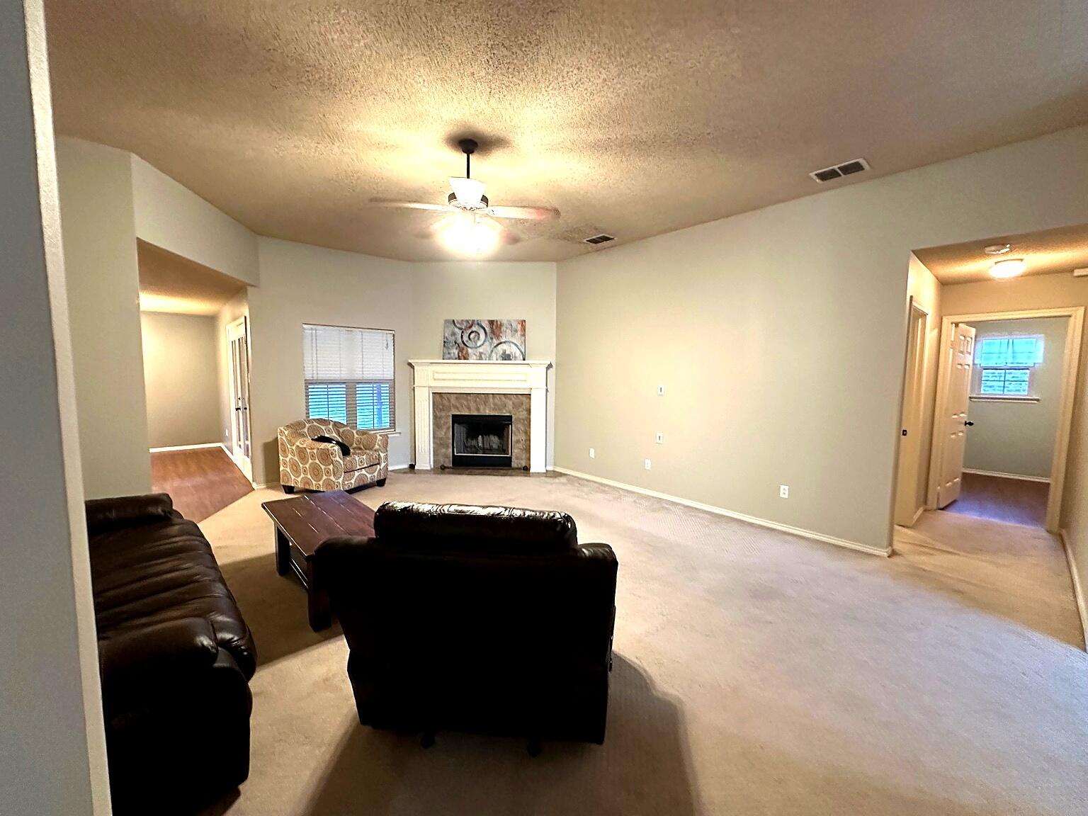 6115 100th Street Lubbock, TX 79424 - Photo 7 of 27 a living room with furniture a fireplace and a chandelier