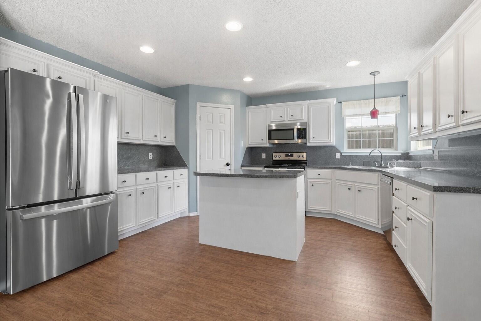 6115 100th Street Lubbock, TX 79424 - Photo 9 of 27 a kitchen with white cabinets stainless steel appliances and a window