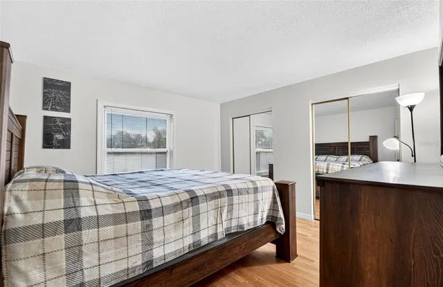 a bedroom with a bed a mirror on the wall and a window