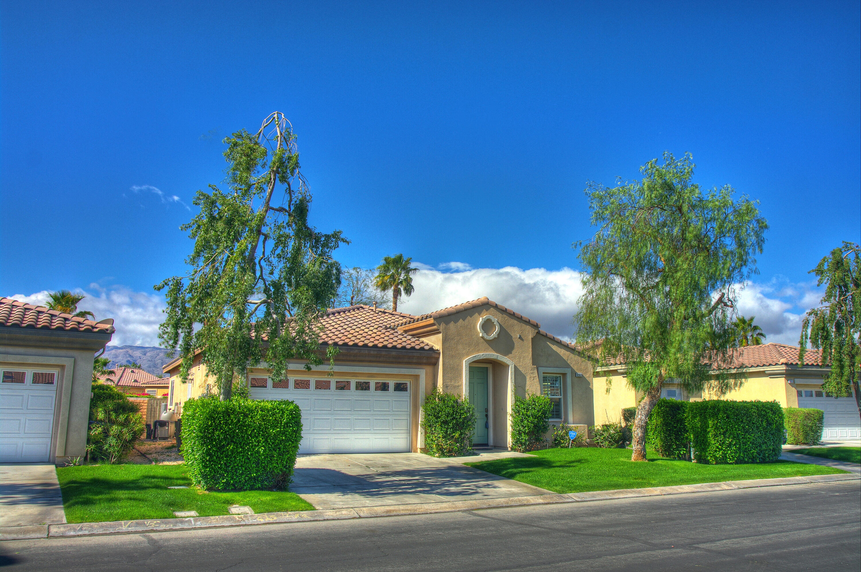 a view of a white house with a flower garden and a tree