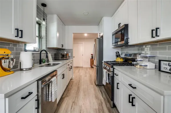 a kitchen with stainless steel appliances a sink a stove top oven a counter space and cabinets