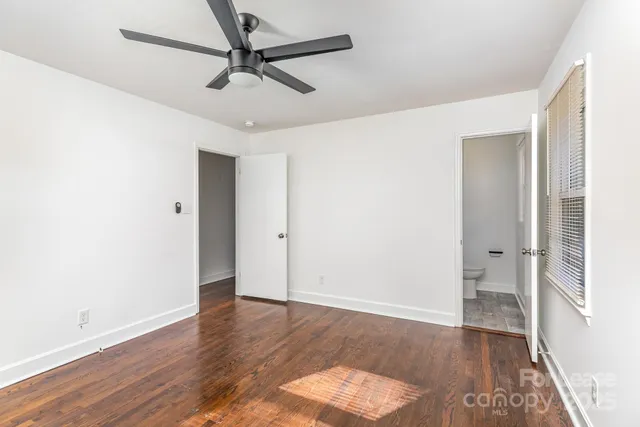an empty room with wooden floor and a ceiling fan