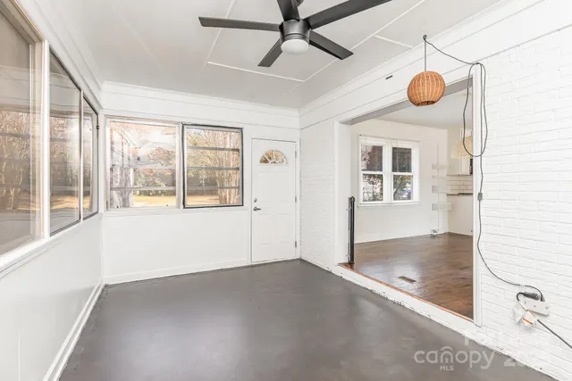 an empty room with windows and fan