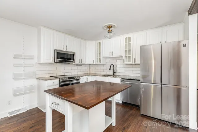 a kitchen with a sink a microwave a refrigerator and cabinets