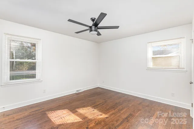 a view of a big room with wooden floor and windows