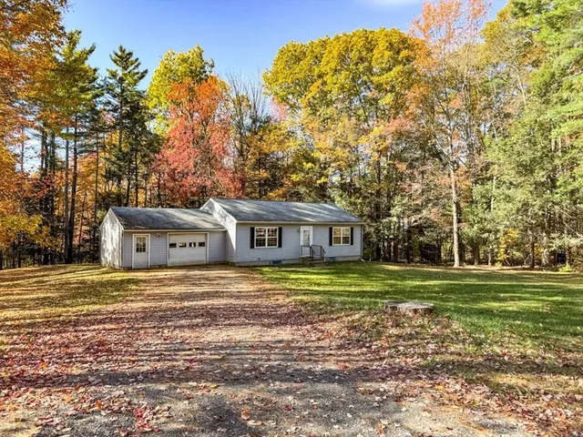 a front view of a house with a garden and trees
