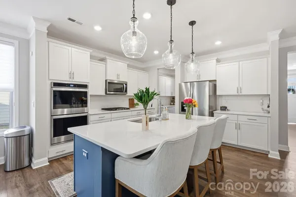 a kitchen with kitchen island a dining table chairs stainless steel appliances and cabinets