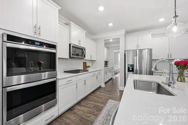 a large kitchen with stainless steel appliances kitchen island granite countertop a refrigerator stove and sink