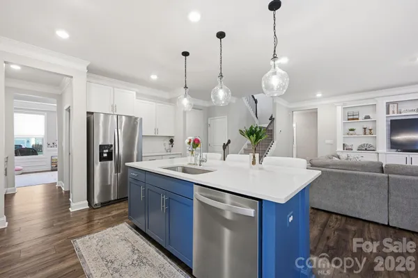 a large kitchen with stainless steel appliances kitchen island granite countertop a stove a refrigerator a oven a kitchen island with couches chairs and wooden floor