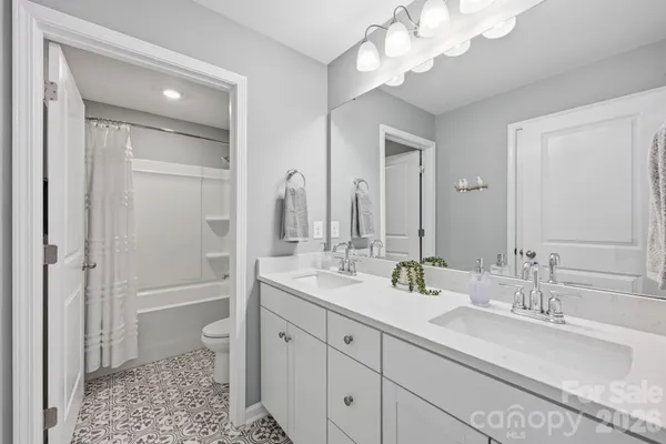 a bathroom with a double vanity sink a toilet and shower