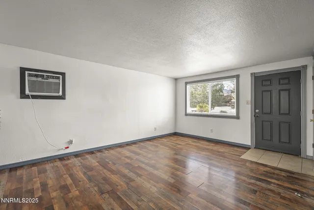 a view of an empty room with window and wooden floor