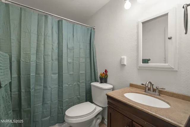 a bathroom with a granite countertop sink toilet a mirror and shower