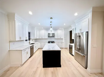 a kitchen with kitchen island stainless steel appliances a sink cabinets and wooden floor