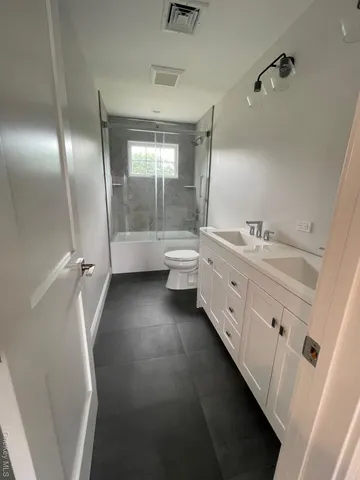 a bathroom with a double vanity sink a toilet and a tub