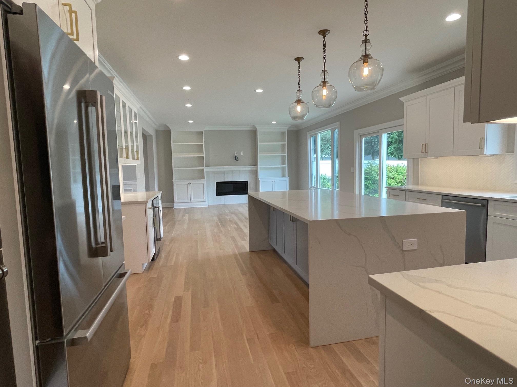 7 Greenway Circle Syosset, NY 11791 - Photo 10 of 10 Kitchen with stainless steel appliances, open floor plan, hanging light fixtures, white cabinets, and light stone countertops