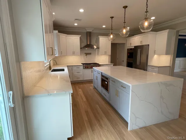 a large kitchen with stainless steel appliances kitchen island a stove a refrigerator a oven and a sink with large countertops