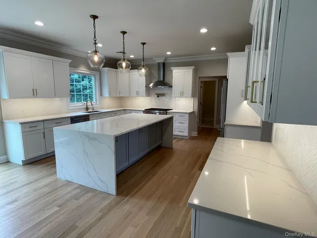 a large kitchen with granite countertop a large counter top a sink stainless steel appliances and cabinets