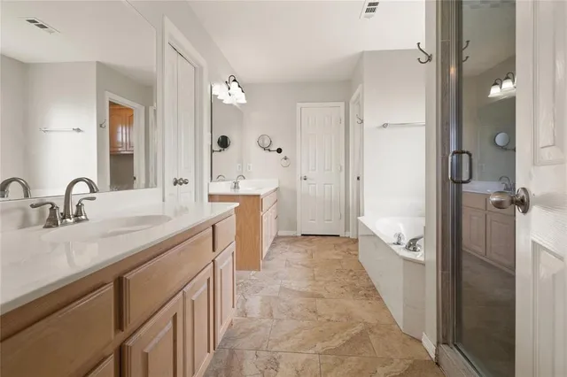 a spacious bathroom with a double vanity sink a mirror a bathtub and shower