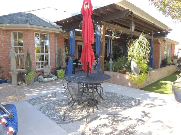 a view of a patio with table and chairs potted plants and large tree