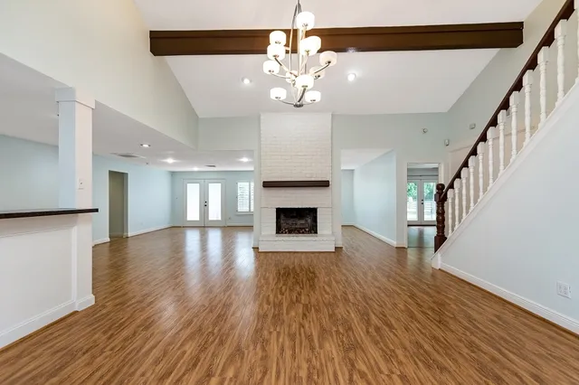 a view of an empty room with wooden floor and a fireplace