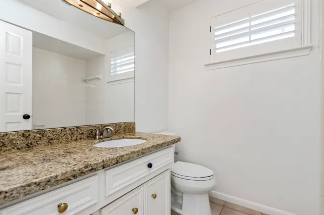 a bathroom with a granite countertop sink a toilet and a window