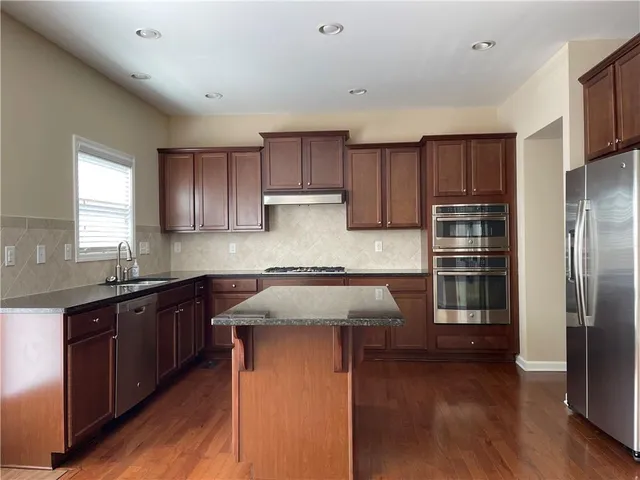 a kitchen with kitchen island granite countertop wooden cabinets a refrigerator and a sink
