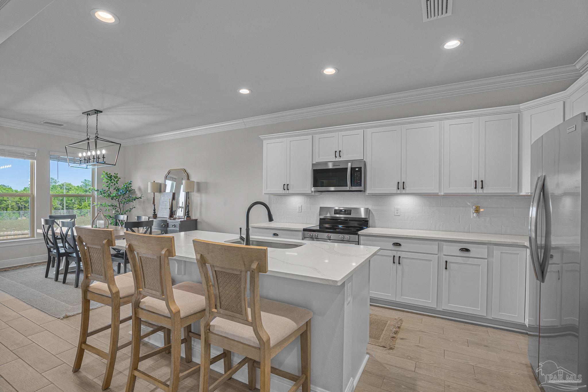 5380 Adeline Circle Pace, FL 32571 - Photo 9 of 35 a kitchen with stainless steel appliances a sink a stove a refrigerator cabinets and dining table