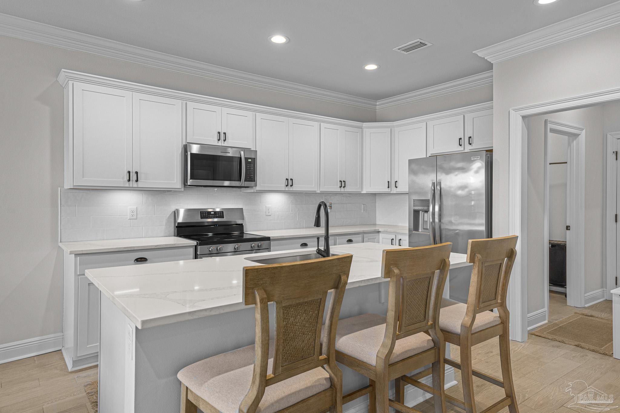 5380 Adeline Circle Pace, FL 32571 - Photo 10 of 35 a kitchen with stainless steel appliances granite countertop a stove a sink a microwave a refrigerator a dining table and chairs with wooden floor