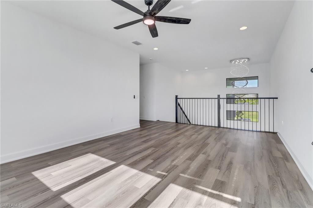 20458 Fair Oak Lane Estero, FL 33928 - Photo 17 of 40 Unfurnished room featuring ceiling fan with notable chandelier and light hardwood / wood-style flooring