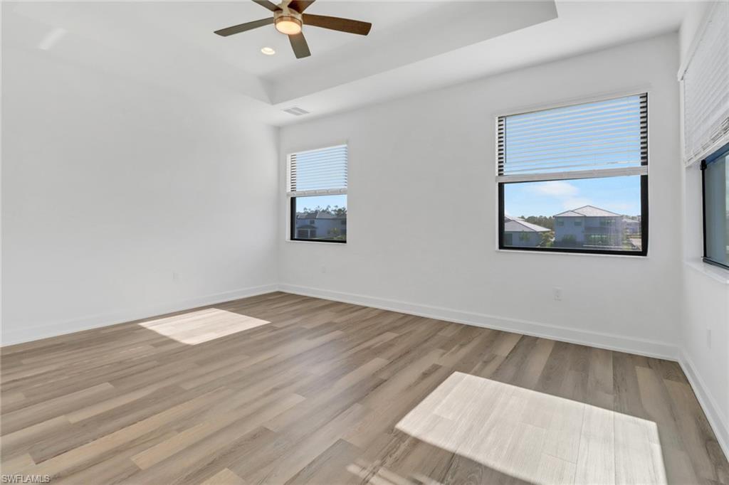 20458 Fair Oak Lane Estero, FL 33928 - Photo 19 of 40 Empty room featuring a healthy amount of sunlight, ceiling fan, and light hardwood / wood-style floors