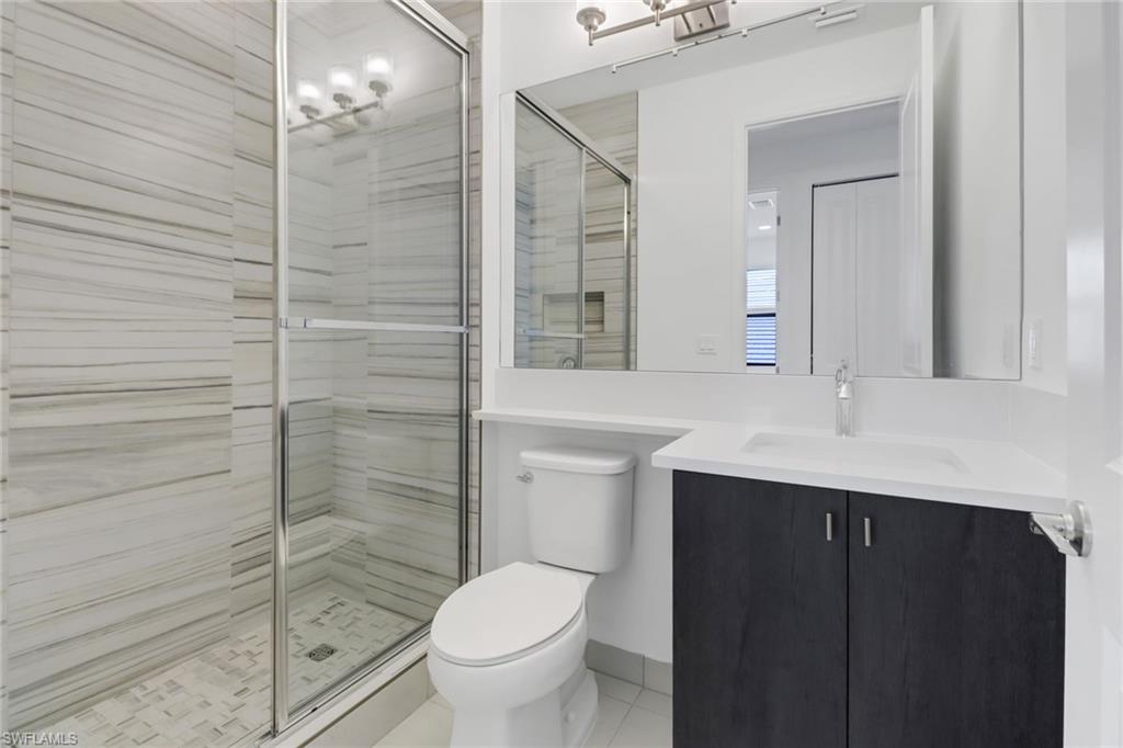 20458 Fair Oak Lane Estero, FL 33928 - Photo 24 of 40 Bathroom featuring a notable chandelier, vanity, toilet, and a shower with door