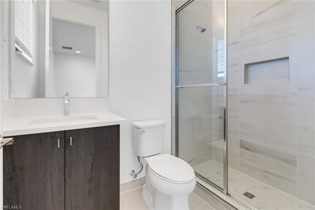 20458 Fair Oak Lane Estero, FL 33928 - Photo 27 of 40 Bathroom featuring tile patterned floors, vanity, toilet, and a shower with shower door